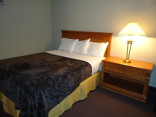 Una habitación de hotel con una cama, una mesita de noche y una lámpara.