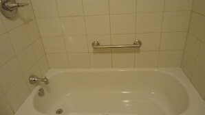 A standard white bathtub with a grab bar, a faucet, and a soap dispenser. - Westmount Motel (South-West Oxford)