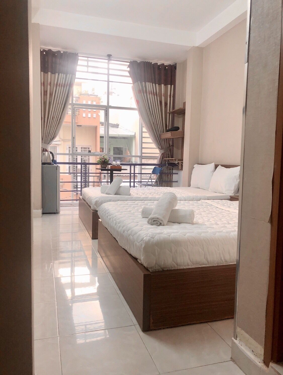Ein modernes Hotelzimmer mit einem großen Bett, einem Balkon mit Blick und einem kleinen Tisch mit einer Pflanze.