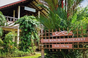 Un letrero de madera con la inscripción 'The Mangrove Hideaway' y 'Koh Chang', rodeado de exuberante follaje.