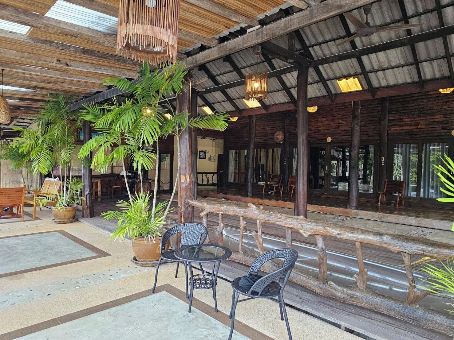 A covered outdoor seating area with wooden furniture and potted plants.