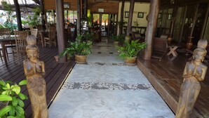 Eine Holzterrasse mit einem Mosaikweg, Pflanzkübeln und Holzstatuen.
