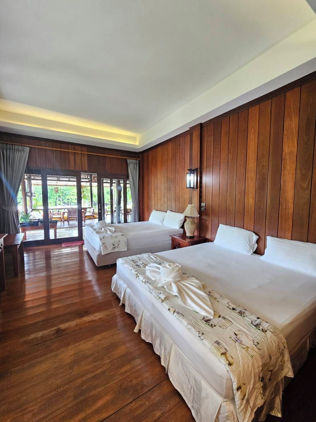 Habitación de hotel con dos camas, paneles de madera, un ventanal y vistas al exterior.