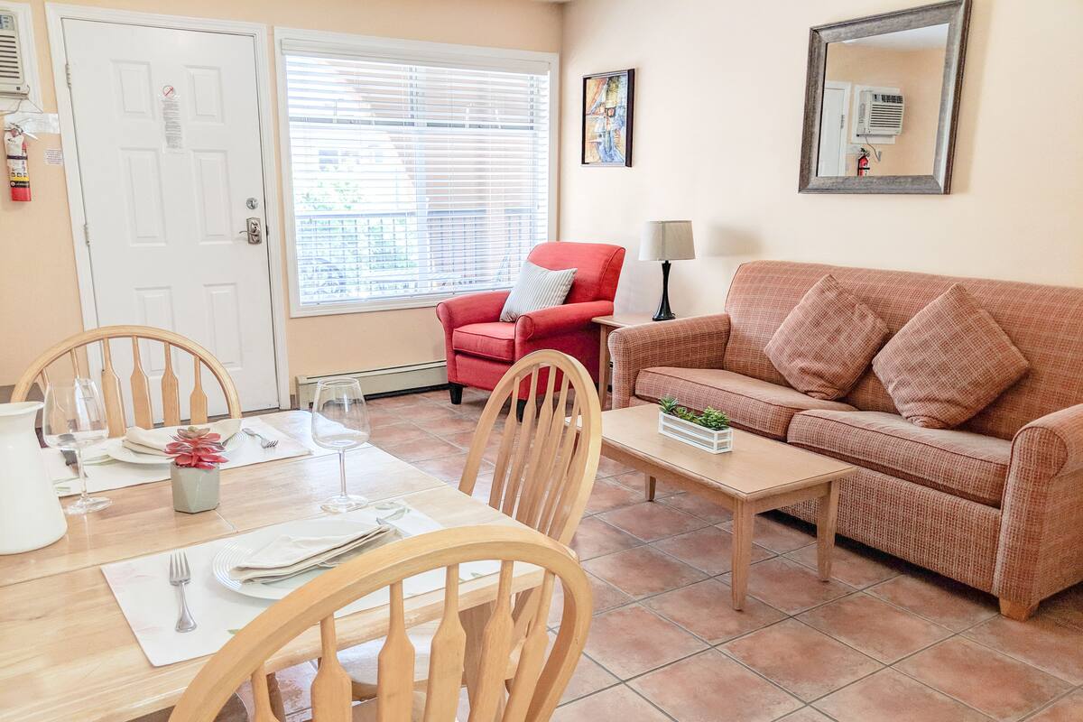 A living room with a dining table, chairs, a red sofa, and a coffee table.