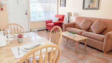 A living room with a dining table, chairs, a red sofa, and a coffee table.