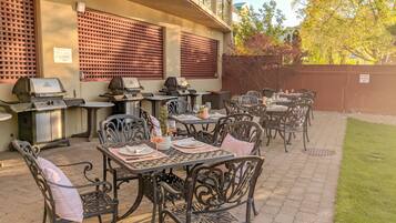 An outdoor patio with multiple tables and chairs, equipped with grills and dining tables set for a meal.