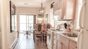 A kitchen with wooden cabinets, a stainless steel sink, and a dining area with wooden chairs and a table. - Desert Surfside Waterfront Accommodations (Osoyoos)