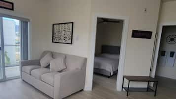 A living room with a sofa, a dining table, and a kitchen area with a stove.