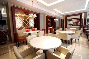 A modern restaurant with round tables and cushioned chairs, featuring a geometric patterned wall and a large window. - Jinjiang Inn Langfang High-Speed Rail Station Yinhe South Road (Langfang)