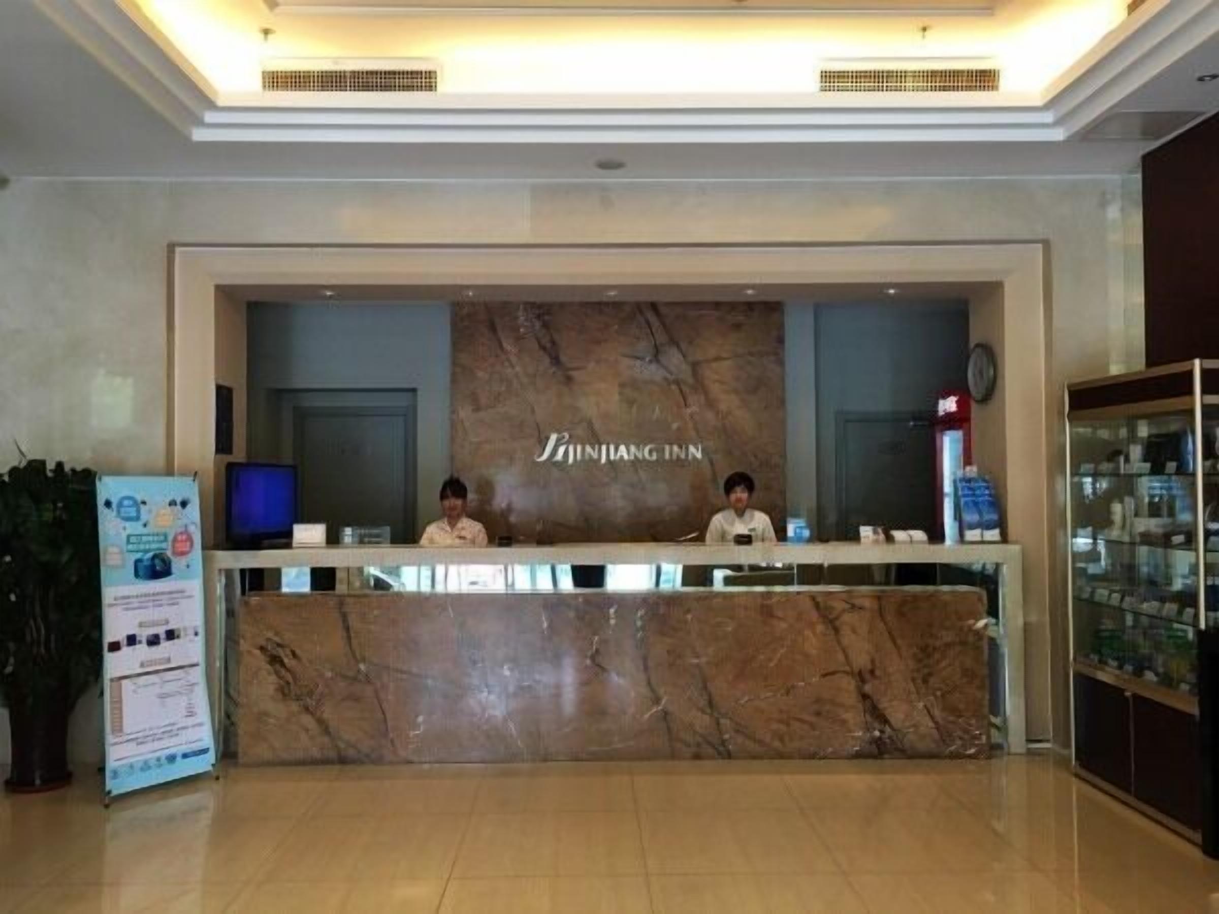 A reception desk with a marble counter and a sign that reads "JINJIANG INN".
