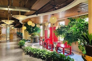 A spacious indoor area with a curved ceiling, red chairs, and potted plants. - Spring Summer Fall Winter International Hotel (Dingxing)