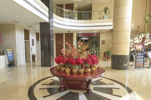A lobby with a central round table, a glass railing, and a large pillar. - Spring Summer Fall Winter International Hotel (Dingxing)