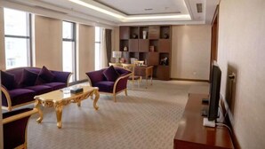 Uma sala de estar moderna com um sofá, poltronas, uma mesa de centro, uma televisão e uma estante.