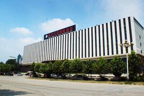A modern building with a prominent sign, a parking lot, and a clear sky. - Spring Summer Fall Winter International Hotel (Dingxing)