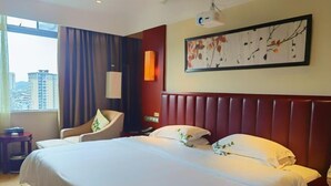 Habitación de hotel con una cama grande, una silla, un escritorio y una ventana con vistas a la ciudad.