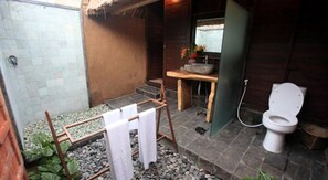 A small bathroom with a toilet, a sink, and a shower area. - TS Hut Lembongan (Lembongan Island)