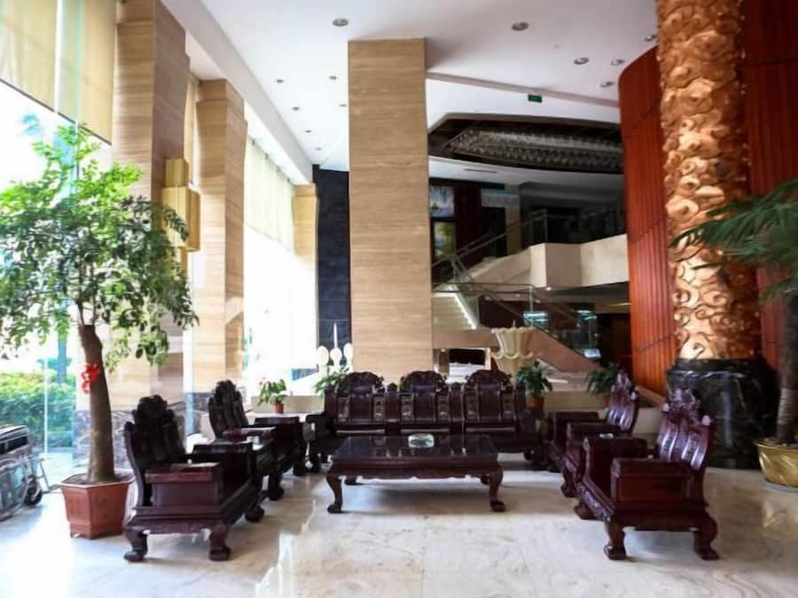 A lobby with a grand staircase, large columns, and a seating area with wooden furniture.