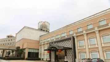 Entrada de hotel com um grande arco, uma torre e estacionamento.