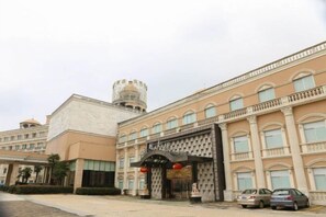 Entrada de hotel con un gran arco, una torre y un estacionamiento.