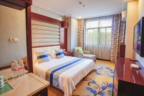 Una habitación de hotel con una cama grande, un escritorio con una silla, un televisor y una ventana con cortinas.