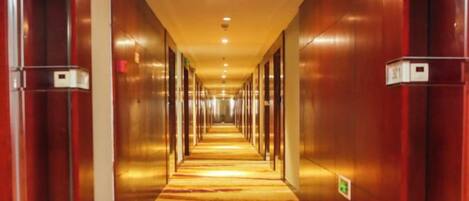 Un largo y estrecho pasillo de hotel con suelo alfombrado y puertas a ambos lados.