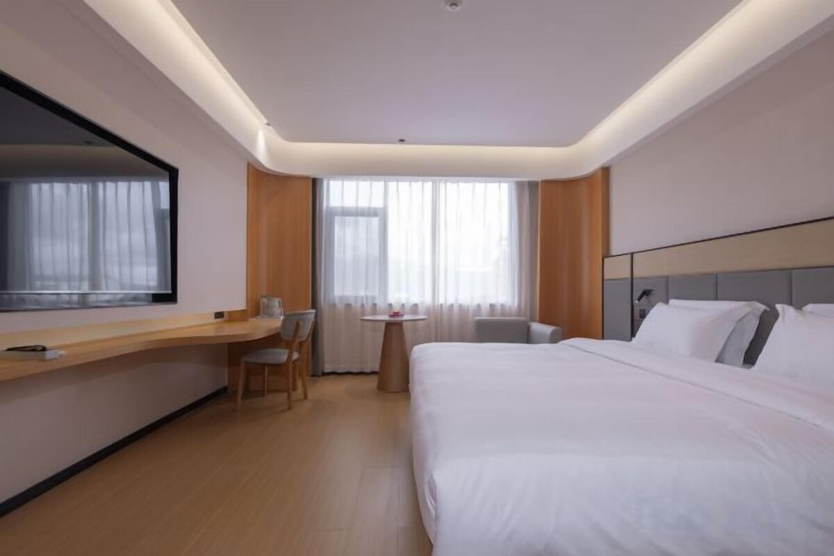 Una habitació d'hotel amb un llit, una taula de treball, una cadira i una televisió.
