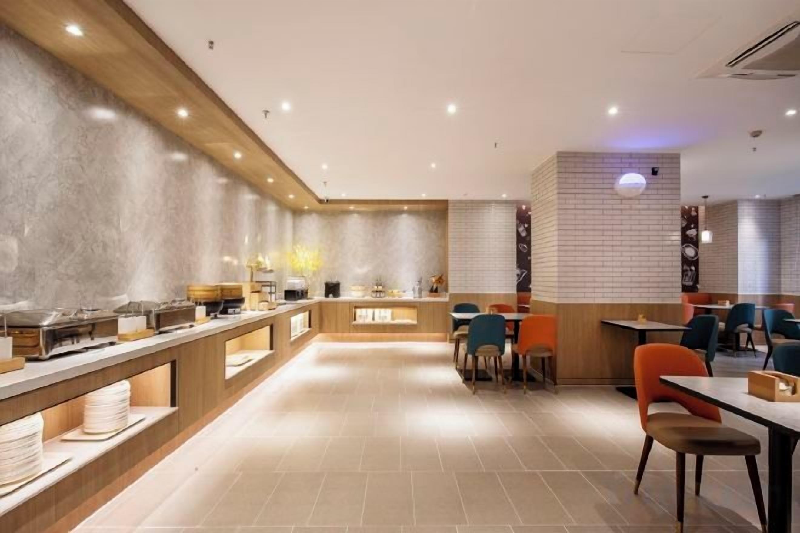 A modern restaurant interior with a long counter, multiple seating areas, and a clean, tiled floor.