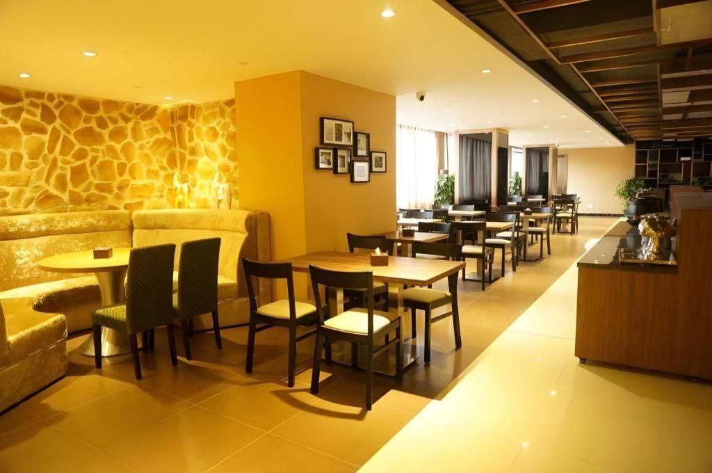 Un hall de hotel con pared de piedra, una recepción y varias mesas y sillas para comer.