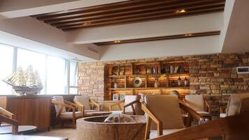 A cozy lounge area with a stone wall, wooden furniture, and a ship model.