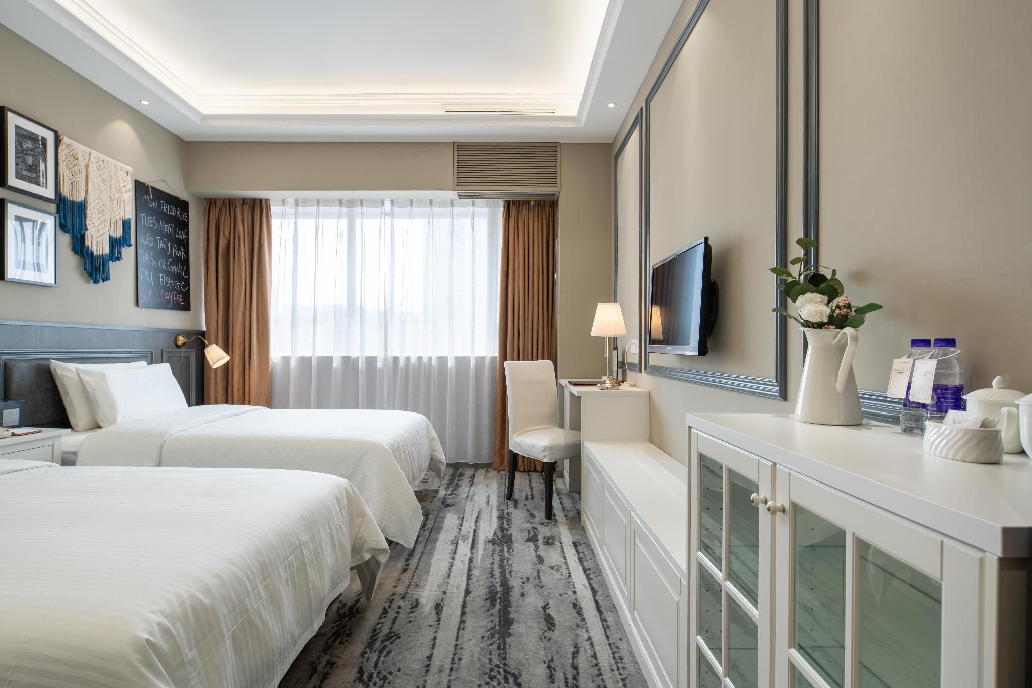 Une chambre d’hôtel avec deux lits, un bureau, une télévision et un minibar.