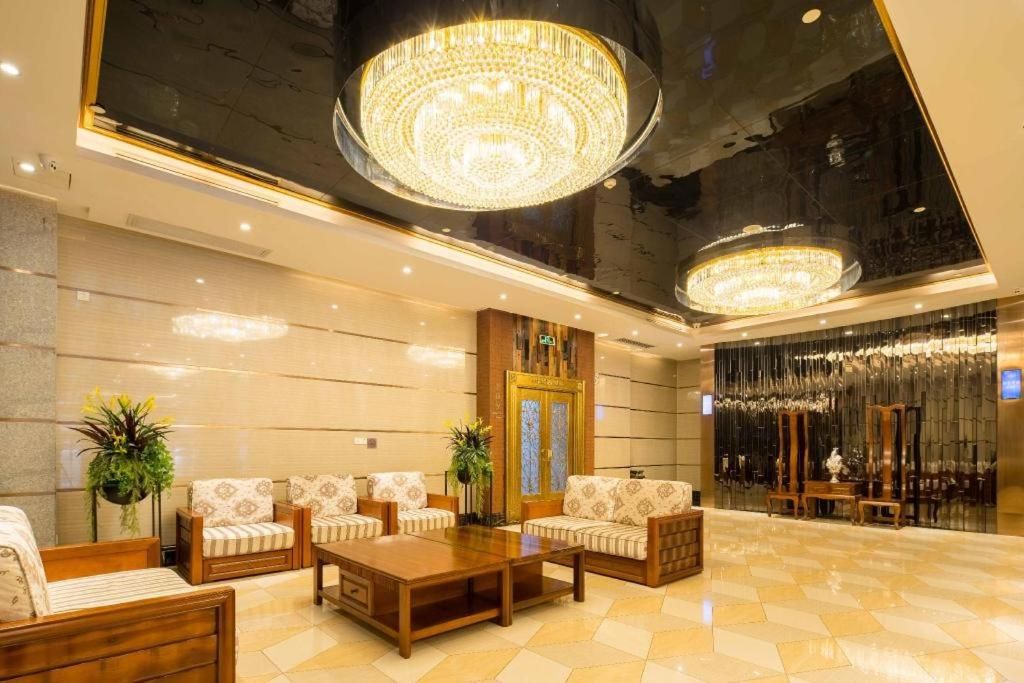 A lobby with a reception desk, seating area, and a large chandelier.