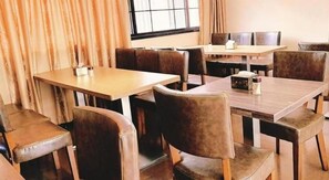 A restaurant interior with multiple tables and booths, leather seating, and a window with curtains. - Gondola Taikoo Hotel (Guangzhou)
