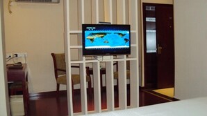 A hotel room with a bed, a television mounted on a white partition, a desk with a keyboard, and a chair. - Greentree Inn Nantong Stadium West Qingnian Road Business Hotel (Nantong)