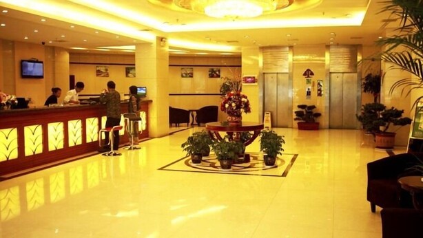 A hotel lobby with a reception desk, seating area, and a central decorative table with plants. - Greentree Inn Nantong Stadium West Qingnian Road Business Hotel (Nantong)