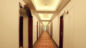 A hotel corridor with a carpeted floor, doors on both sides, and a ceiling with recessed lighting. - GreenTree Inn Zhoushan Putuo Donggang Hotel (Zhoushan)