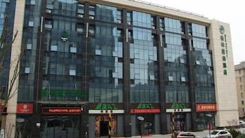A modern building with multiple storefronts, including a green sign with white text, a red sign with white text, and a yellow sign with black text.