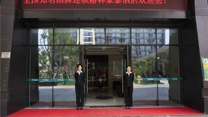 A hotel entrance with a red carpet and two uniformed staff members standing at the doorway. - GreenTree Inn Zhoushan Putuo Donggang Hotel (Zhoushan)