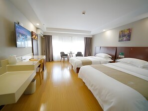 Ein Hotelzimmer mit zwei Betten, einem Schreibtisch, einem Stuhl, einem Fernseher und einem Fenster mit Vorhängen.