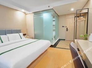 A modern hotel room with a large bed, a desk, a chair, a wardrobe, and a glass-enclosed closet. - Greentree Inn Shanghai Baoshan Yanghang Shuichan Road Hotel (Shanghai)