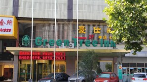 A hotel with a prominent 'Green Tree Inn' sign, a parking area with several cars, and a sign for '格林豪泰酒店'. - Greentree Inn Shanghai Baoshan Yanghang Shuichan Road Hotel (Shanghai)