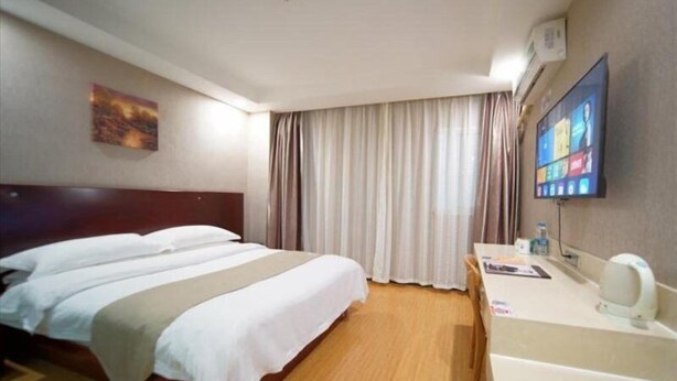 A hotel room with a bed, a desk with a computer, and a TV on the wall. - Greentree Inn Shanghai Baoshan Yanghang Shuichan Road Hotel (Shanghai)
