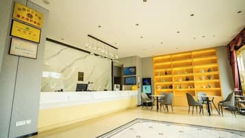 Ein Hotel-Rezeptionsbereich mit Marmorzauber, einem Empfangstresen, einer Sitzecke mit Stühlen und einer Wand mit Regalen, die Gegenstände zeigen.