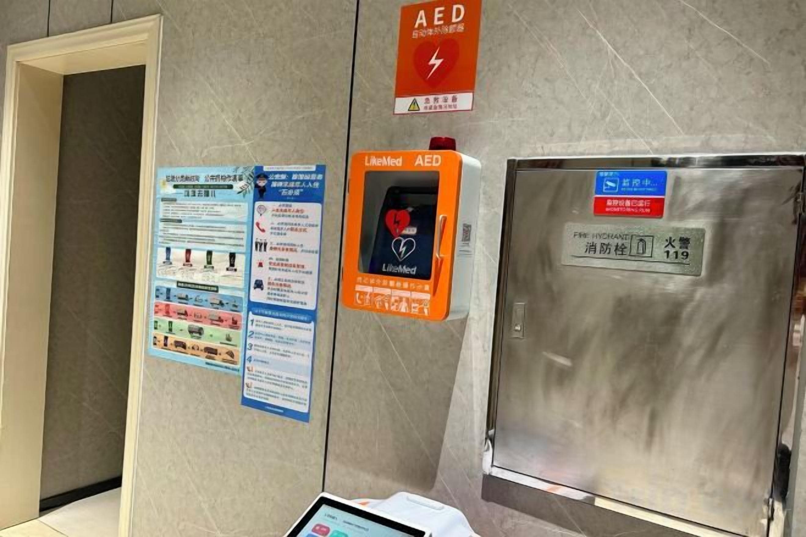 An AED device, emergency contact information, and a fire extinguisher on a wall.
