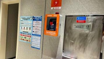 An AED device, emergency contact information, and a fire extinguisher on a wall.