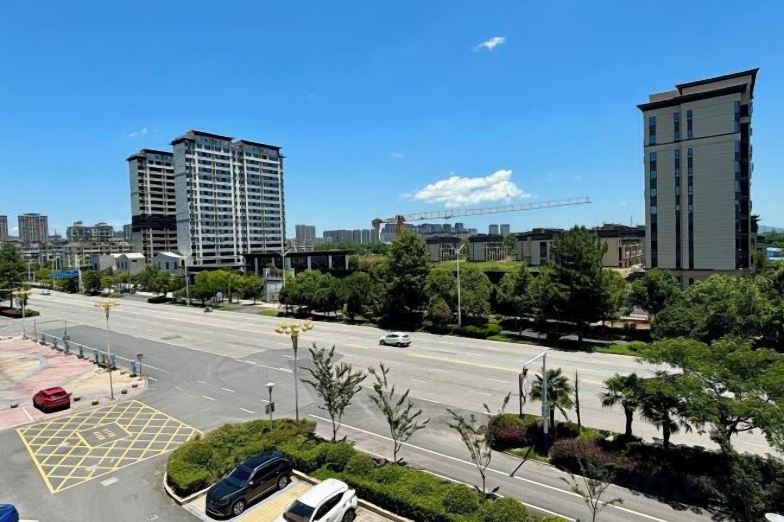 A multi-level building with a modern design, surrounded by greenery and a clear sky.