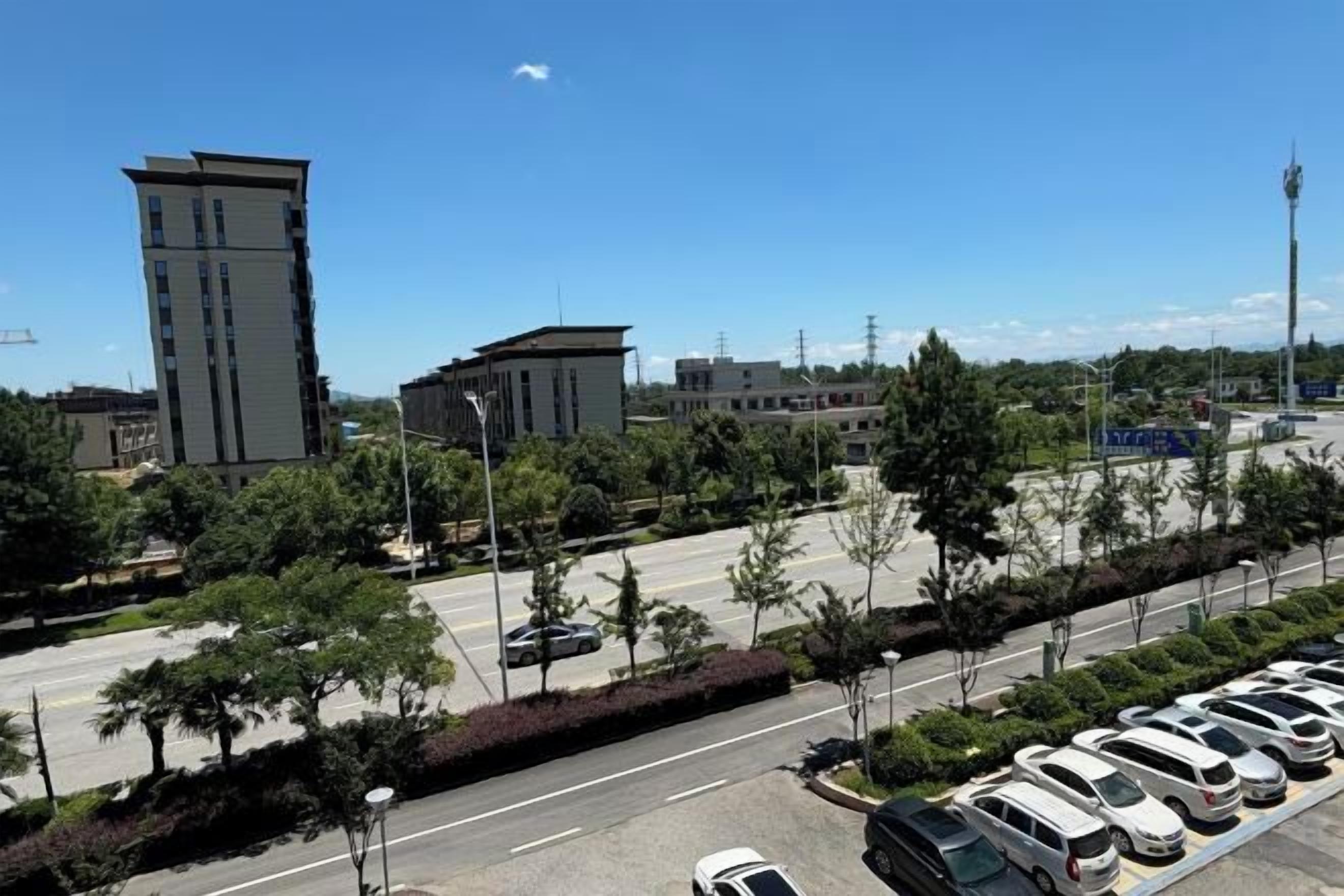 Un parking rempli de voitures, un ciel dégagé et des bâtiments en arrière-plan.