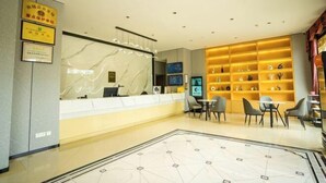 Zona de recepción de un hotel con un mostrador de mármol, un área de asientos con mesas y sillas, y una pared con diplomas enmarcados.