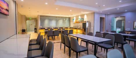 A conference room with a long table and chairs, a kitchen area with a bar, and a separate dining area with tables and chairs.