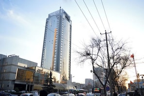 Un edificio alto de diseño moderno, rodeado de otros edificios y un cielo despejado.
