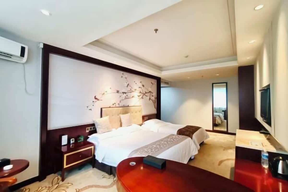 A hotel room with a large bed, a bedside table, a TV, and a mirror.